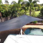 home with shade sail over patio and pool